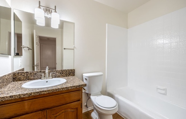 a bathroom with a sink toilet and tub and a mirror