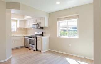 an empty kitchen with white cabinets and a window
