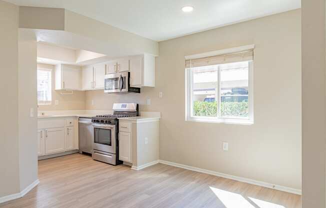 an empty kitchen with white cabinets and a window