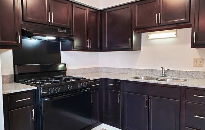 Kitchen in a 1 bedroom apartment with black appliances and dark wood cabinets at Carriage House West.