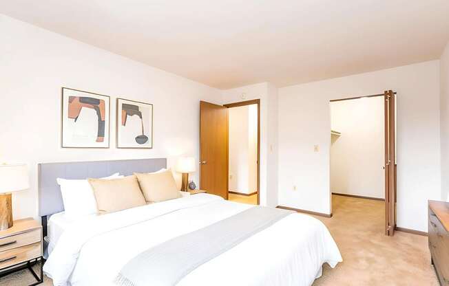 A bedroom with a large bed and two framed pictures on the wall.