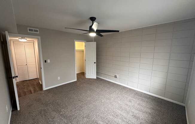A room with a ceiling fan and tile walls.