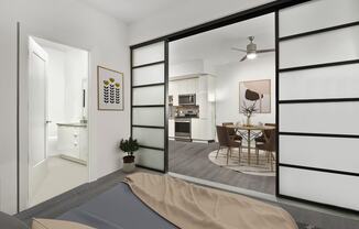 a bedroom with a bed and sliding doors that open to the kitchen and dining area at SLX Atlanta, Georgia, 30341