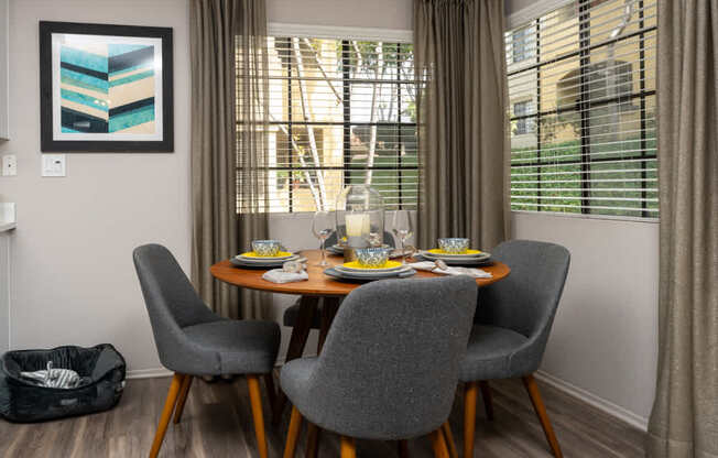 A dining room with a table set for two and a grey chair.