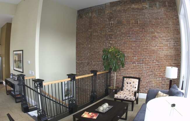 a living room with a brick wall and a couch and a chair