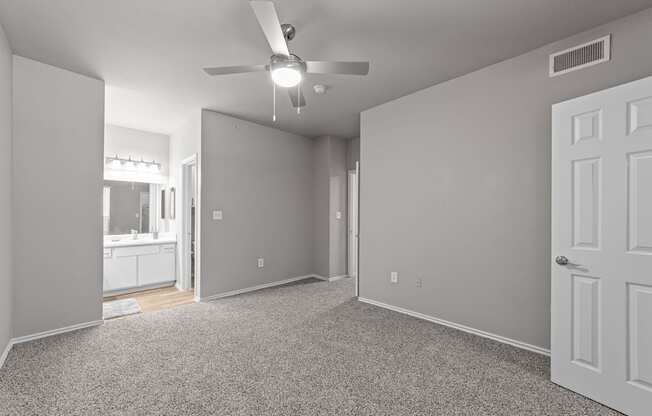 A room with a ceiling fan and carpeted floor.