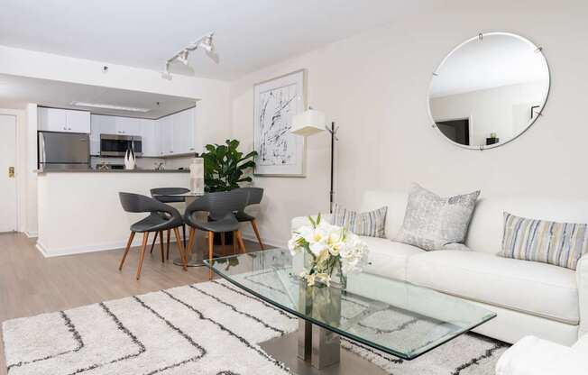 A modern living room with a glass coffee table and a white sofa.
