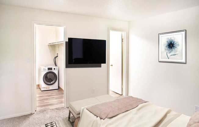 A bedroom with a bed, a television, and a washing machine.