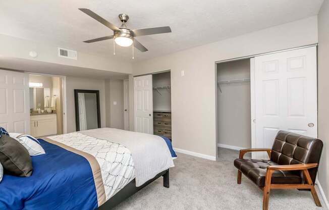 A bedroom with a blue bedspread and a brown leather chair.