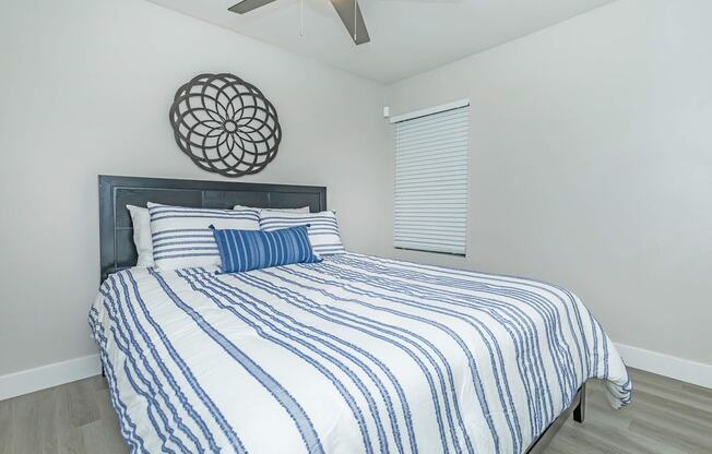 A bed with a blue and white striped comforter and a round decorative piece on the wall.