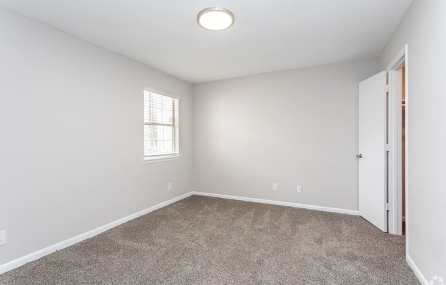 an empty bedroom with carpet and a door to a closet