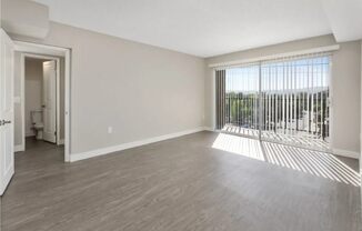 an empty living room with a large window and wood flooring