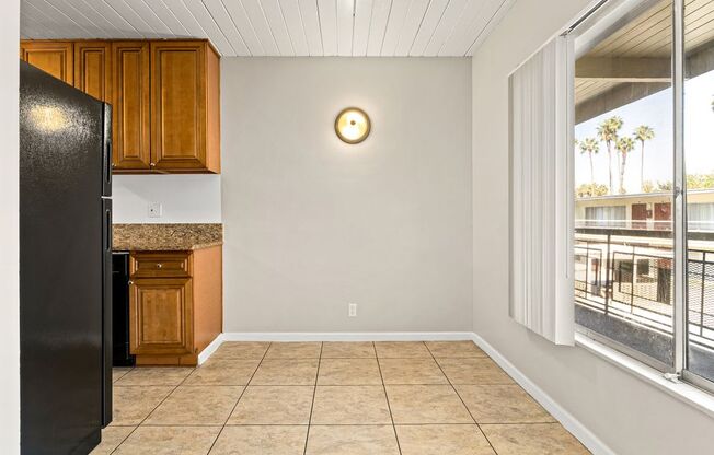 A kitchen with a black refrigerator and wooden cabinets.