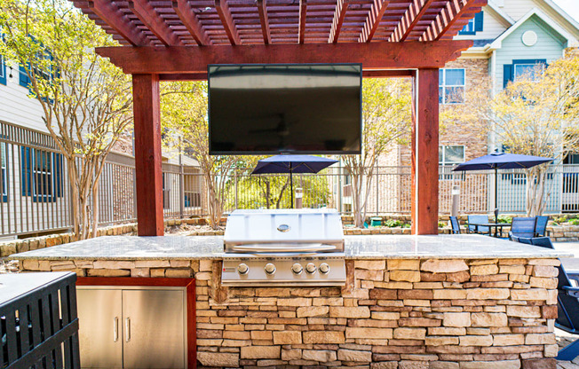 an outdoor entertaining area with a grill and a television