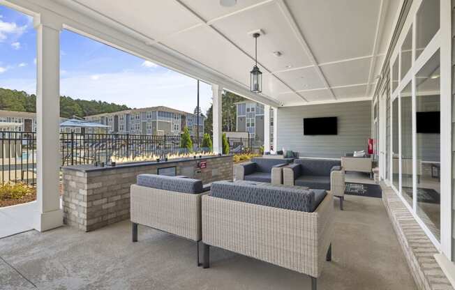 a covered patio with couches and chairs and a wall of windows