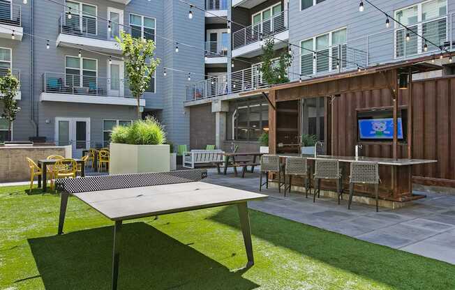 A table tennis table is in the middle of a grassy area.
