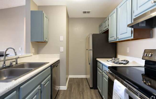 a kitchen with stainless steel appliances and blue cabinets at Aqua Bay Apartments in Naples, FL 34116