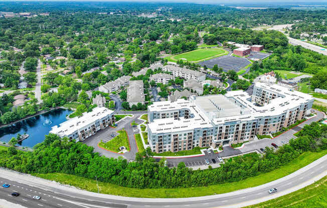 A large building complex is surrounded by a green landscape and a body of water.