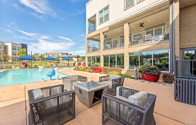 A patio with a table and chairs overlooking a pool.