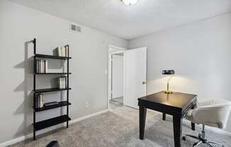 an empty room with a desk and a chair and a book shelf