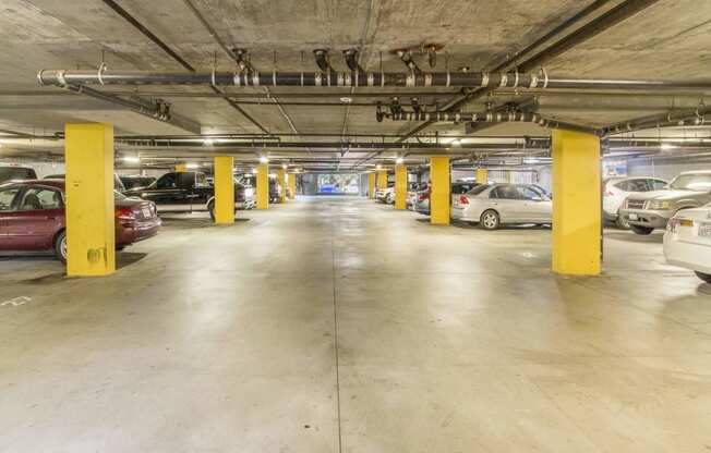 a parking garage with cars and yellow pillars at Dronfield Astoria Apartments, Sylmar