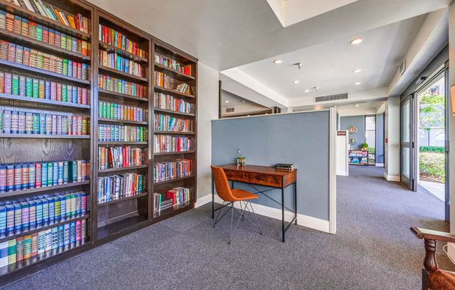 a home library with a desk and chair in front of a large bookshelf