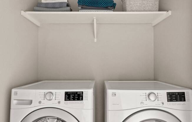 Two white front loading washing machines in a laundry room.