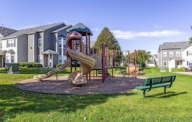 a playground with a slide and a bench in front of a building