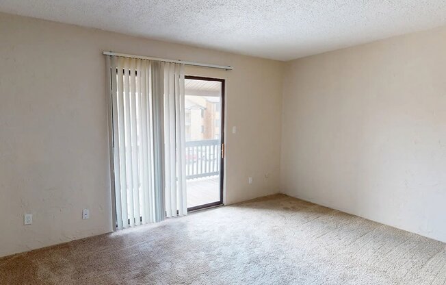 an empty living room with sliding glass doors to a balcony