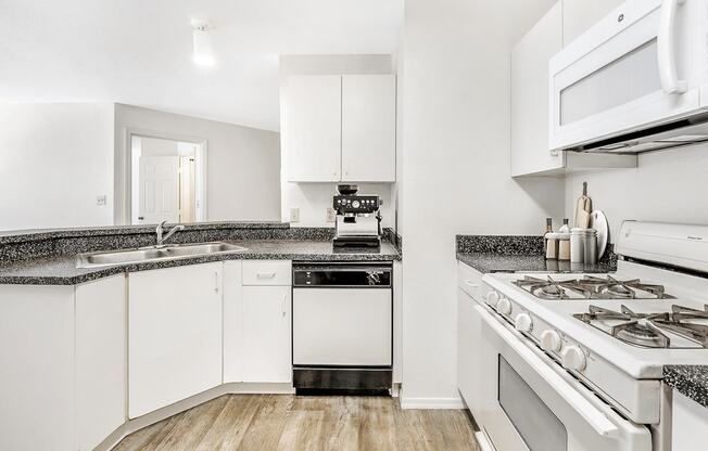 Virtually staged kitchen with white cabinets, gray countertop, white appliances, gas stove and wood flooring