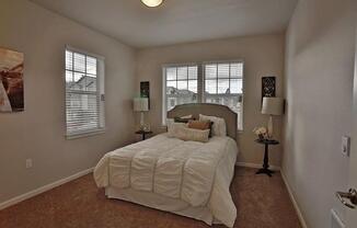 a bedroom with a large bed and two windows