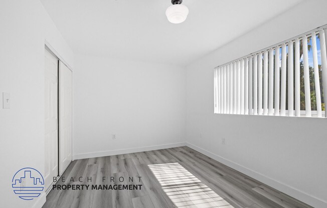 an empty room with wood flooring and a window