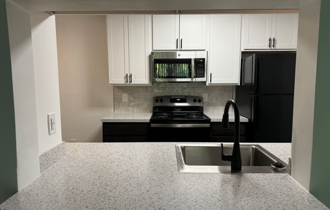 a kitchen with white cabinets and black appliances and a sink