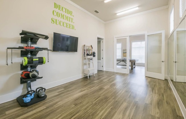 a workout room with weights and a tv on the wall