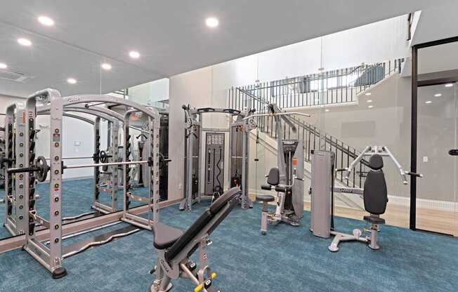 A gym with a variety of equipment including a squat rack, leg press machine, and a bench press.