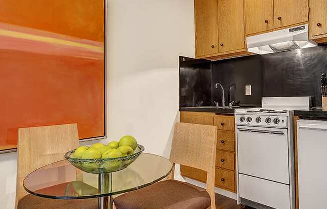 a kitchen with a white stove top oven next to a table with a bowl of fruit on