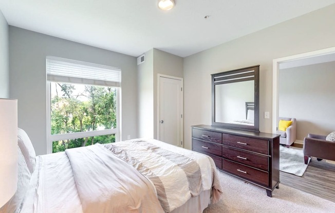 a bedroom with a bed and a dresser and a window