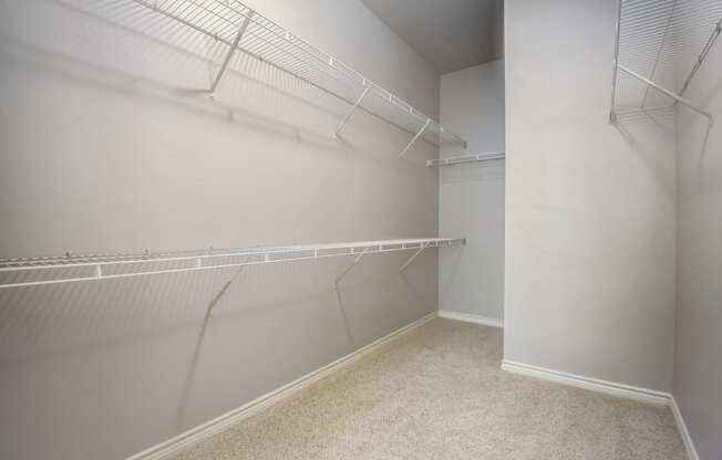 the walk in closet of a studio apartment with shelves and racks