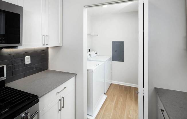 a kitchen with white cabinets and a door to a laundry room