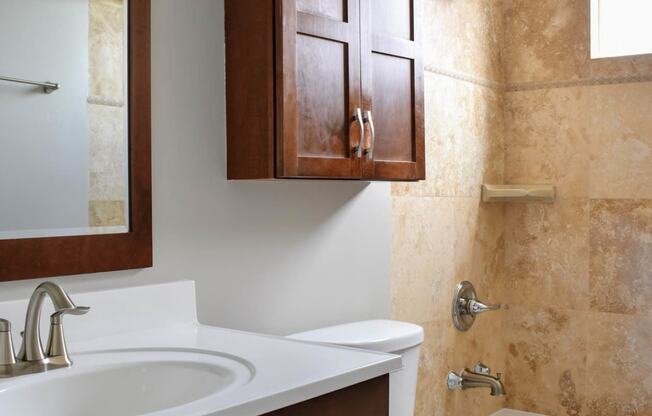 View of bathroom with inlaid sink, vanity, mirror, storage over toilet, toilet, tub shower combo with well lit window above