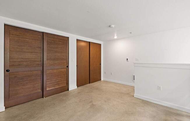 A room with two brown doors and a white wall.