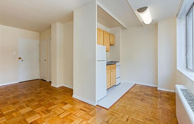 vacant living area with hardwood flooring, view of front entrance and kitchen at brunswick house apartments in dupont circle washington dc