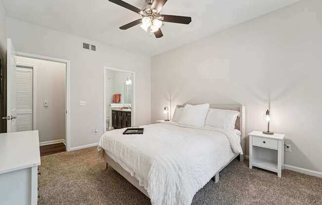 A bedroom with a bed, nightstand, and a ceiling fan.