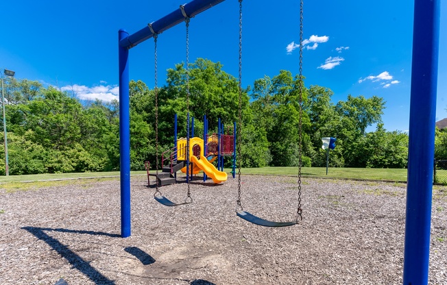 a playground with a yellow swing set in a park