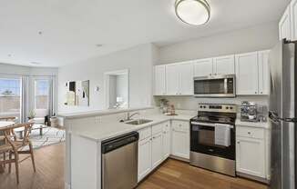A modern kitchen with white cabinets and stainless steel appliances.