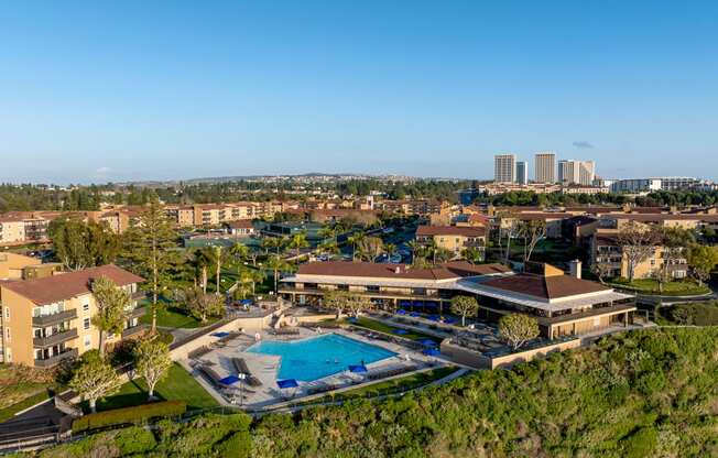 an aerial view of a resort with a swimming pool and a city in the background