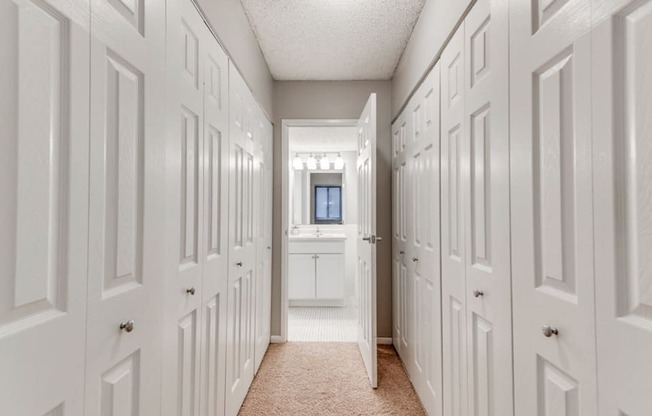 In between two rows of closets with a bathroom at the end of the hall