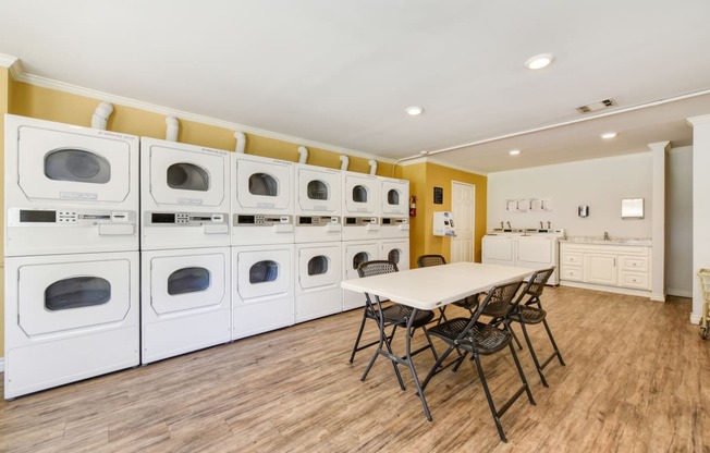 On-Site Laundry Center with multiple laundry machines.  There is a table and chairs in he center of the room.