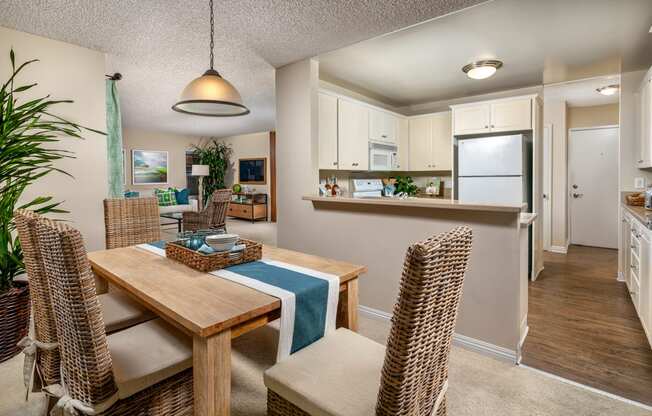 a dining room and kitchen with a wooden table and chairs