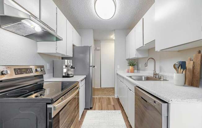 Modern kitchen at Peak 88 Apartments in Renton, WA with stainless steel appliances and wood-style flooring